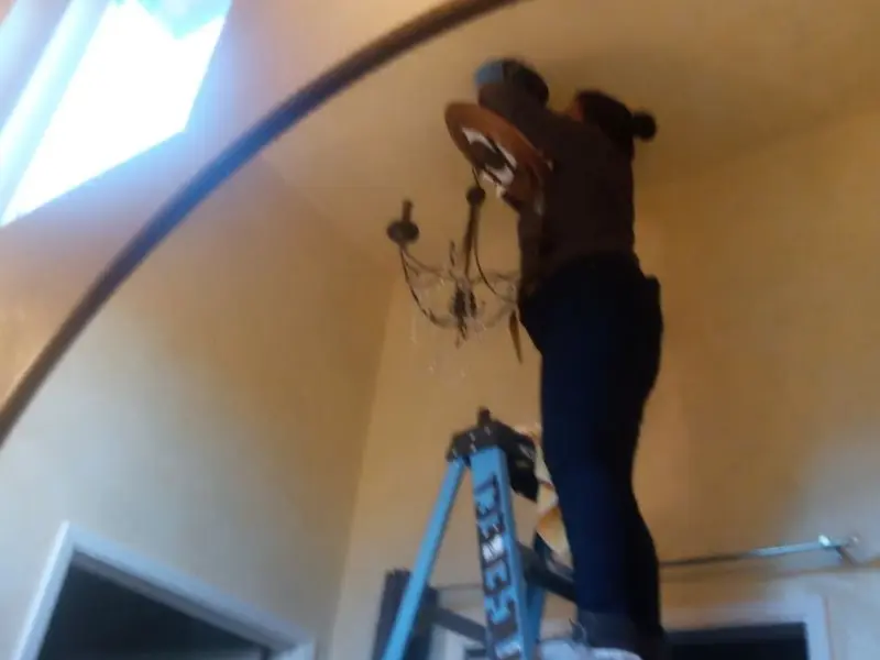 Electrician installing a chandelier in a Long Lake residence